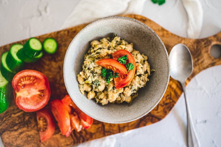 A top view of a nutritious chickpea salad with fresh tomatoes and cucumbers on a wooden board.