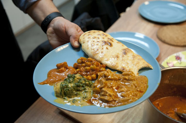 A vibrant blue plate featuring a variety of Indian curries and naan bread, served indoors.