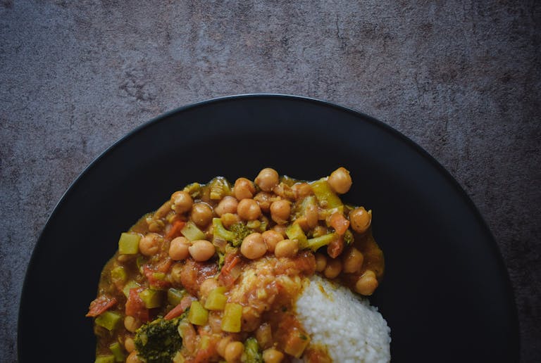 Top view of a vegan chickpea and rice dish served on a slate background, highlighting its vibrant colors and textures.